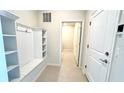 Functional mud room with built-in shelving, coat hooks, and access to the laundry area at 16248 Saint Kitts Cir, Clermont, FL 34714