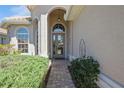 Inviting home entrance featuring an arched doorway, a brick walkway, decorative shrubbery, and a neutral tan color scheme at 512 Weston Pl, Debary, FL 32713