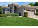 Charming home featuring a lush green lawn, a brick driveway, manicured shrubbery, and a neutral tan color scheme at 512 Weston Pl, Debary, FL 32713