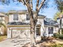 Inviting two-story home with a two-car garage and mature trees in the front yard at 8380 Baywood Vista Dr, Orlando, FL 32810