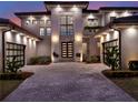 An expertly-lit contemporary home with a gray brick driveway, modern garage doors, and green plants at 8521 Lake Nona Shore Dr, Orlando, FL 32827