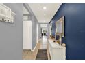 Inviting hallway with neutral paint, decorative mirror, and tile flooring leading to a bright living area at 11207 Amber Ridge Dr, Zellwood, FL 32798