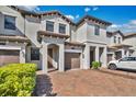 Townhouse exterior showing a brick paved driveway, neutral paint, brown garage doors, and landscaping at 1298 Royal St George Blvd, Davenport, FL 33896