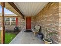 Covered brick porch with a chair and plants, welcoming entrance with a red front door at 2010 Overlook Dr, Winter Haven, FL 33884