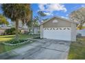 Close up of the single-story home with a large garage and manicured yard with palm tree at 2242 Dancy Trl, Clermont, FL 34714