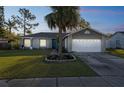 Charming single-story home with a well-manicured lawn and inviting blue front door at dusk at 2242 Dancy Trl, Clermont, FL 34714