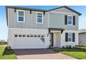 Two-story home with a combination of vertical and horizontal siding, a brick driveway, and an attached garage at 312 Castle Dr, Lake Alfred, FL 33850