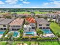 Aerial view of a home with a red tiled roof, backyard pool, patio furniture and surrounding golf course and community at 411 Muirfield Loop, Reunion, FL 34747