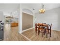 Dining area featuring wood-look tile flooring and stylish chandelier, adjacent to open kitchen at 4907 Culdesac Ct, St Cloud, FL 34772