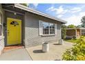 Close up of front porch with a bright yellow door and concrete sitting area with plants at 520 Oriole Dr, Lakeland, FL 33803