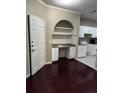 Cozy office nook with built-in desk, shelving, drawers and dark wood-look flooring, next to an open door and white kitchen cabinets at 860 N Orange Ave # 149, Orlando, FL 32801