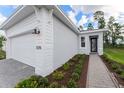 Exterior view showcasing the light stucco facade and a brick walkway to front door at 1276 Jackson Hole Ct, Deland, FL 32724