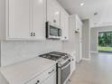 Modern kitchen with white cabinetry, stainless steel appliances, and herringbone backsplash at 1276 Jackson Hole Ct, Deland, FL 32724