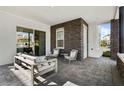 Charming covered patio with comfortable seating, stone wall accents, and stylish flooring at 14004 Gullstrand Ave, Orlando, FL 32827