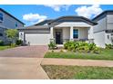 Single Gathering home featuring a brick driveway, two-car garage, and a cozy front porch at 2311 Bear Peak Road, Minneola, FL 34715