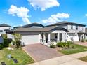 Charming single Gathering home featuring a brick driveway, two-car garage, and a cozy front porch at 2311 Bear Peak Road, Minneola, FL 34715