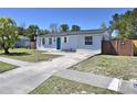 View of the home's exterior featuring a driveway and a well-manicured lawn, complemented by lush trees at 2480 Alamanda Ave, Deltona, FL 32738