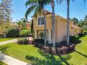 Side exterior view of a tan home with tile roof, mature landscaping, column details and a paver driveway at 2816 Northampton Ave, Orlando, FL 32828