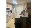 Well lit kitchen includes a breakfast bar, white appliances, and light wood cabinets at 5471 Vineland Rd # 7108, Orlando, FL 32811