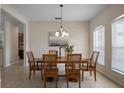 Dining room with wood table, decorative chandelier, and view into the kitchen, features tile flooring at 7299 Vista Park Blvd, Orlando, FL 32829