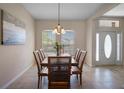 A dining room features tile flooring, a wood table with seating for six, chandelier, and natural light through the windows at 7299 Vista Park Blvd, Orlando, FL 32829
