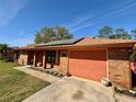 One-story home with a red brick exterior, solar panels, and an attached garage at 1062 Stillwater Ave, Deltona, FL 32725