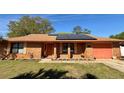 Inviting brick home featuring a matching colored garage door, solar panels, and flower beds at 1062 Stillwater Ave, Deltona, FL 32725