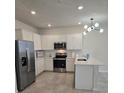 Well-equipped kitchen with stainless steel appliances, white cabinetry, and a stylish light fixture at 11151 Rising Sun St, Orlando, FL 32829