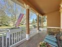 Cozy front porch featuring brick flooring, white railings with planters, and comfortable seating with views of the street at 120 Crepe Myrtle Dr, Groveland, FL 34736