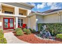 Close up view of a home's column-supported entry and bright red front door at 14149 Islamorada Dr, Orlando, FL 32837