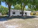 A well-kept single-story home with mature trees, a white exterior and a neat front yard on a sunny day at 2429 Yale Ave, Sanford, FL 32771
