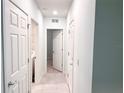 Hallway with doors leading to laundry room, bathroom and bedroom with neutral-toned walls and tile floors at 398 Citrus Isle Loop, Davenport, FL 33837