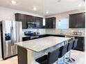 Modern kitchen features stainless steel appliances, granite countertops, and a large island with seating at 398 Citrus Isle Loop, Davenport, FL 33837