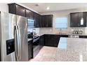 This updated kitchen has stainless steel appliances, stylish dark cabinetry, and granite countertops at 398 Citrus Isle Loop, Davenport, FL 33837