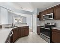 Well-lit kitchen featuring updated stainless steel appliances, tile backsplash, and dark wood cabinetry at 4231 Mendenwood Ln, Orlando, FL 32826