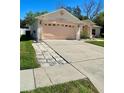 View of the home's driveway and garage with landscaping and sidewalk at 6037 Hickory Grove Ln, Port Orange, FL 32128