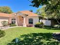 Well-maintained home with a lush green lawn, pretty landscaping, and a charming pastel color palette at 6037 Hickory Grove Ln, Port Orange, FL 32128