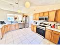 Spacious kitchen featuring modern stainless steel appliances, wood cabinets, and tile flooring at 608 Robin Ln, Kissimmee, FL 34759