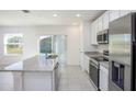 Modern kitchen featuring granite countertops, stainless steel appliances, and a kitchen island with a sink at 6599 Lullaby Way, Mascotte, FL 34753