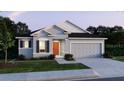 Attractive single-Gathering home showcasing a two-car garage, neutral paint, dark shutters and an inviting front yard at 6611 Lullaby Ln, Mascotte, FL 34753