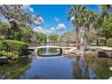 Scenic view of a pond with a charming bridge, surrounded by lush greenery and palm trees, creating a peaceful retreat at 700 Melrose Ave # L-23, Winter Park, FL 32789