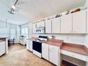 Well lit kitchen equipped with white cabinets, white appliances, and a pink countertop at 72 Saint Kitts Cir, Winter Haven, FL 33884