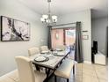 Elegant dining area with marble table set for a meal, complemented by a modern chandelier and decor at 8845 Candy Palm Rd, Kissimmee, FL 34747