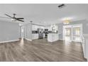 Bright living space features wood-look floors, ceiling fan, neutral paint, and seamless transition to kitchen at 1259 Freeport Dr, Deltona, FL 32725