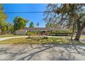 Well-maintained one-story home with an American flag, manicured lawn, and mature trees creating a serene setting at 1285 Seminole Ave, Longwood, FL 32750