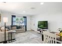 Cozy living room with neutral decor, wood-look flooring, a comfortable couch, and a bright window at 284 Mississippi Woods Ln, Orlando, FL 32824