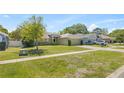 Single-story home featuring a well-maintained lawn, mature trees, and convenient two-car garage at 33845 Emerald Pond Loop, Leesburg, FL 34788