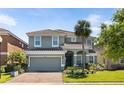 Daytime view of a charming two-story home featuring a tile roof, brick driveway, and lush landscaping at 4416 Shiva Loop, Kissimmee, FL 34746