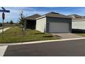 Home exterior with a two-car garage and well-maintained lawn, and a view of the neighborhood at 5111 Lake Hamlin Trl, Winter Garden, FL 34787