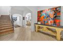 Elegant foyer showcasing wood floors, arched doorways, a staircase, and a stylish console table with vibrant artwork at 851 Georgia Ave, Winter Park, FL 32789